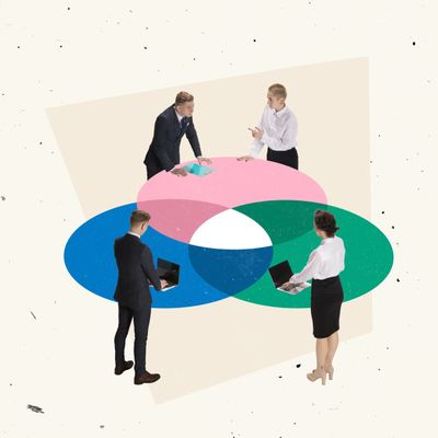 Four businesspeople interact around a colorful Venn diagram on the floor.
