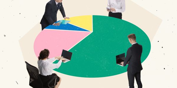 Four professionals collaborate around a large colorful pie chart table with laptops and documents.