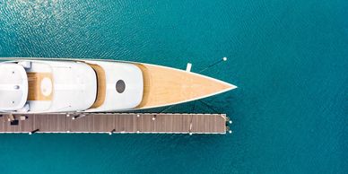 A yacht docked at a pier on clear blue water.