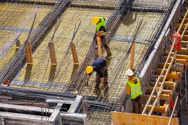 Three workers on a steel-reinforced construction site.