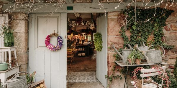Rustic flower shop entrance with wreaths and watering cans.