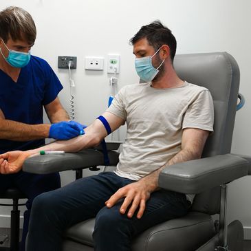 Man wearing a mask getting blood drawn in a clinic.