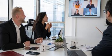 A hybrid business meeting with in-person and virtual participants.