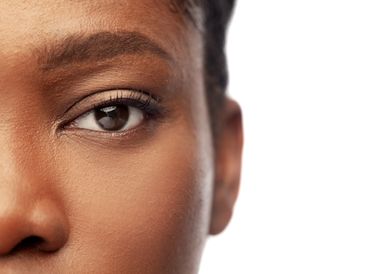 Close-up of a brown eye with detailed skin texture and eyelashes.