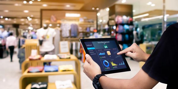 Person using a tablet for store management in a retail clothing store.