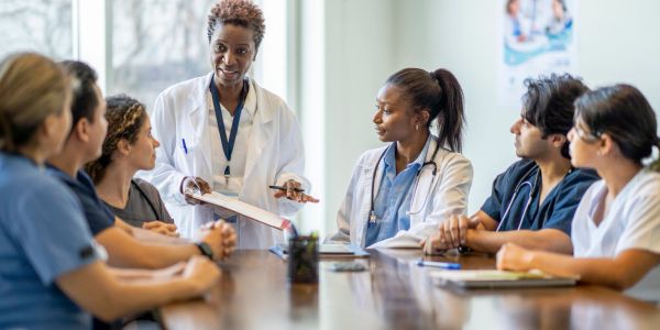 Medical team meeting with a doctor leading.