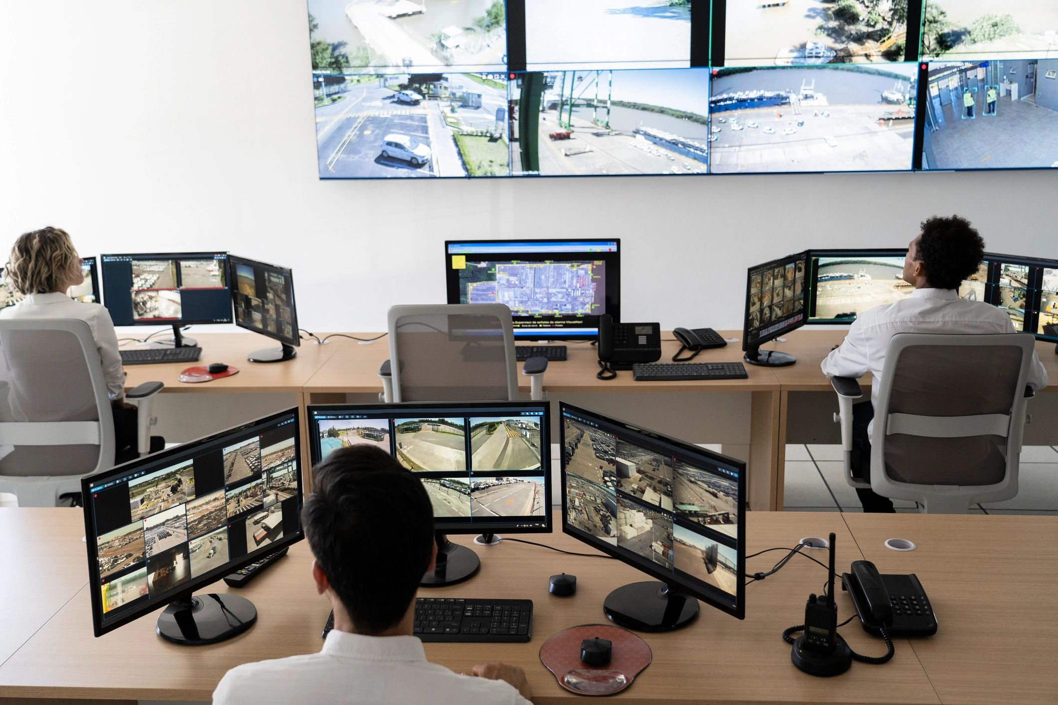 Personas monitorean múltiples pantallas de seguridad en una sala de control.