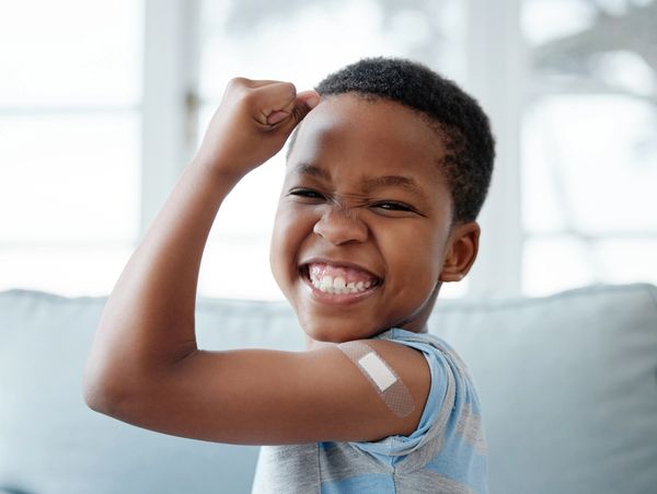 Smiling boy showing a bandage on his arm after vaccination.