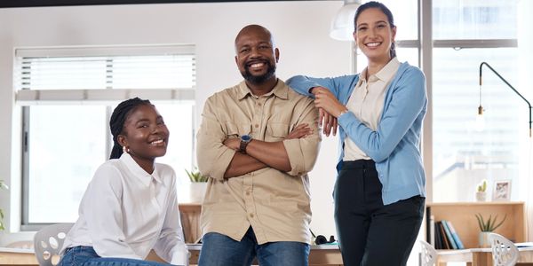 Three diverse colleagues smiling confidently in a modern office space.
