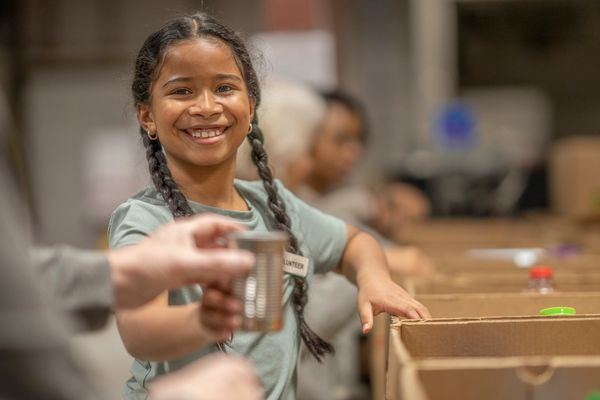 Smiling girl volunteering with boxes.