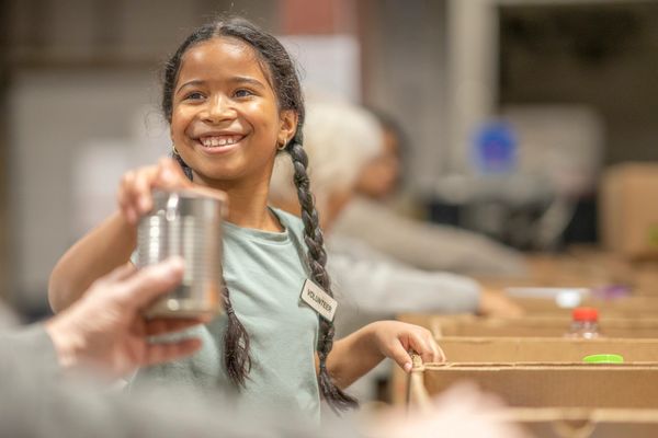 Girl smiling reaching for glass.