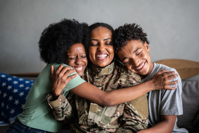 Soldier mother embracing son and daughter at home