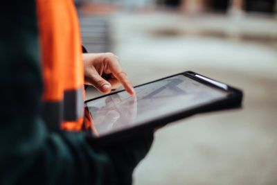 Person using a tablet, wearing a safety vest.