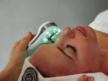 Facial treatment device glowing on woman's skin.