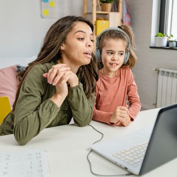 Woman and girl using laptop for an online activity together.