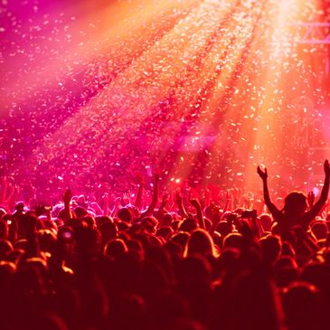 Crowd enjoying a vibrant concert with confetti and bright lights.
