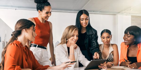 Group of women collaborating around a tablet.