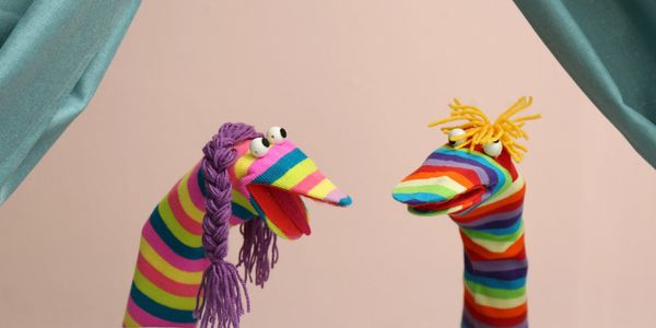 Two colorful striped sock puppets with yarn hair face each other.