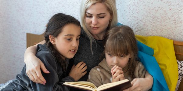 Woman reading a book with two young girls.