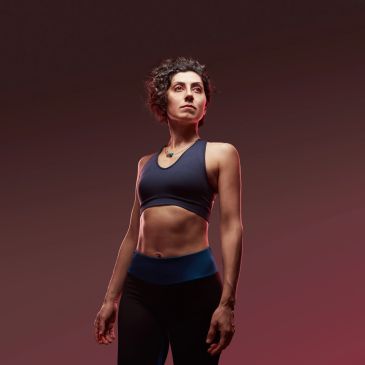 Confident woman in sportswear against a dark red background.