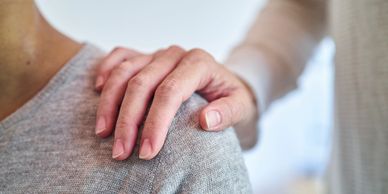 A comforting hand on someone's shoulder showing support and care.