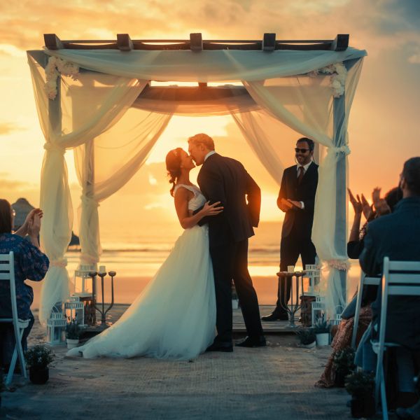 Couple kissing at a beach wedding during sunset.