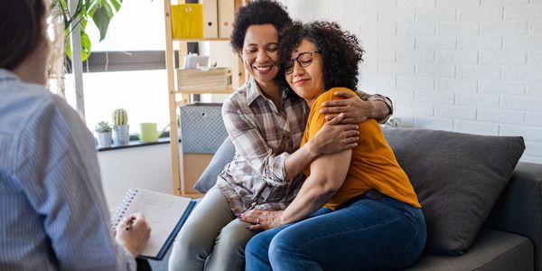 Two women share a warm hug during a counseling session.