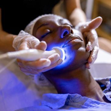 Woman receiving facial light therapy treatment.