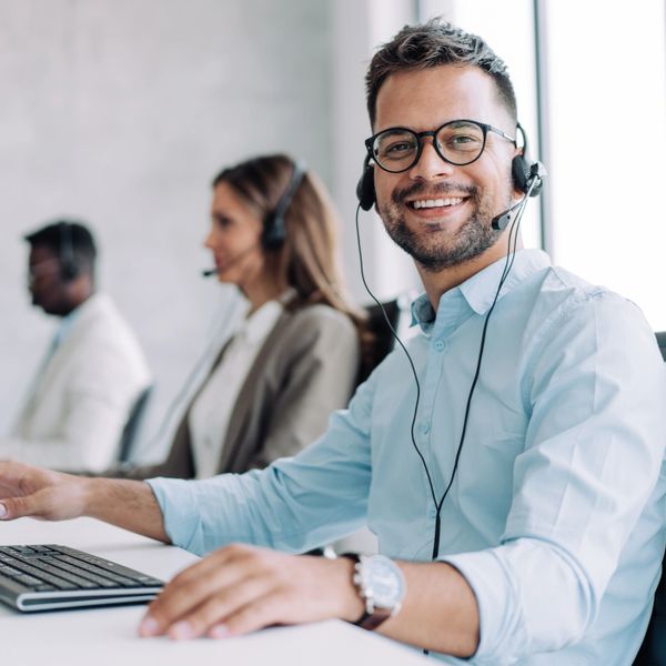 Smiling customer service representative wearing a headset at a call center.