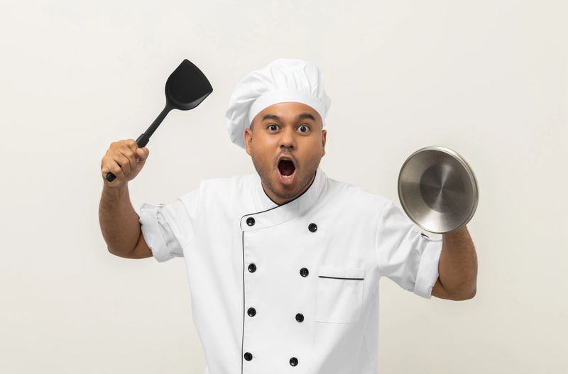 Chef warrior. Young asian man masterchef holding Armed and ready to go out to cook. Kitchen utensils turner and pot lid. Cooking indian man Occupation People in kitchen restaurant