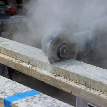 Person cutting a stone slab with a power tool.