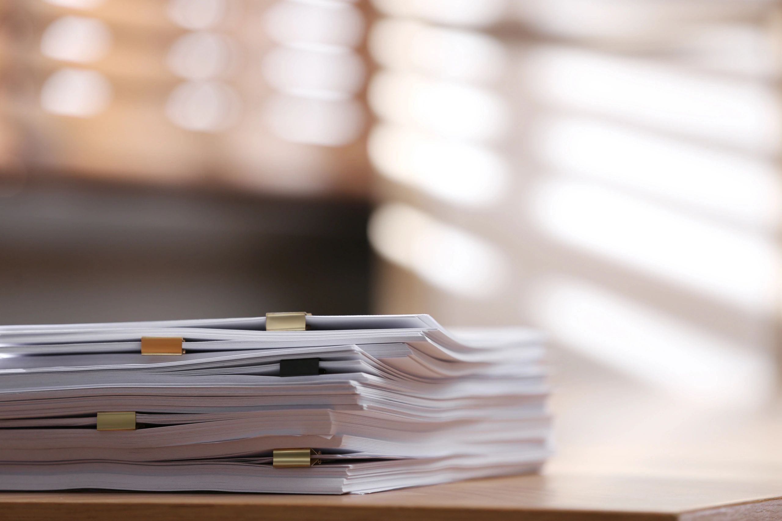 Stacks of paper documents with binder clips on a table.