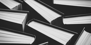 Black and white photo of scattered books lying closed.