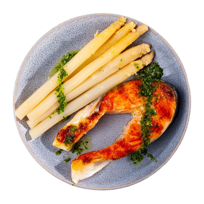 Fresh salmon steak with bunch of roasted asparagus. Isolated over white background