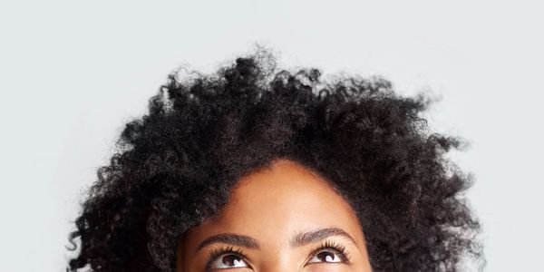 Close-up of a woman with curly hair looking upwards.
