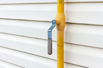 Yellow gas valve against white siding.