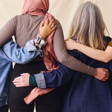 Three people embracing each other from behind.
