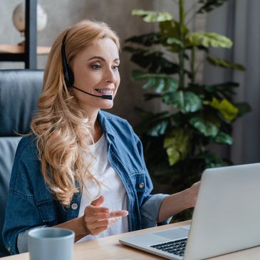 Woman working with headset at laptop.