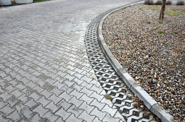 Curved paved pathway with gravel garden bed beside it.