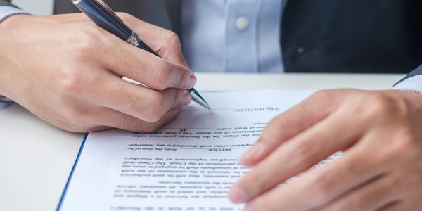 A person signing a formal document with a pen.