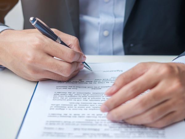 Person in suit signing a contract with a pen.