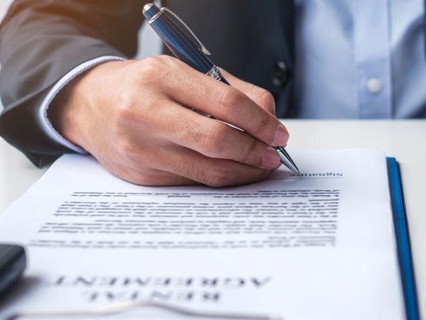 Businessman signing a rental agreement with a pen.