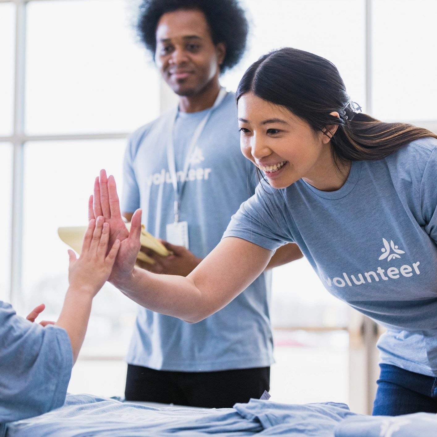 Volunteers giving a high-five to a child in a bright community center.