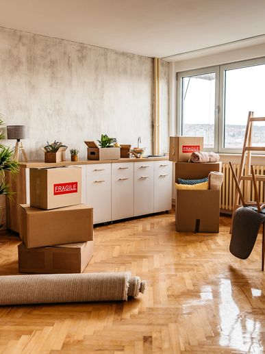 Boxes and a rolled carpet in a bright room.