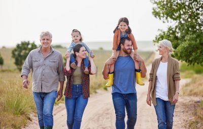 Three generations of family walking outdoors on a dirt path.