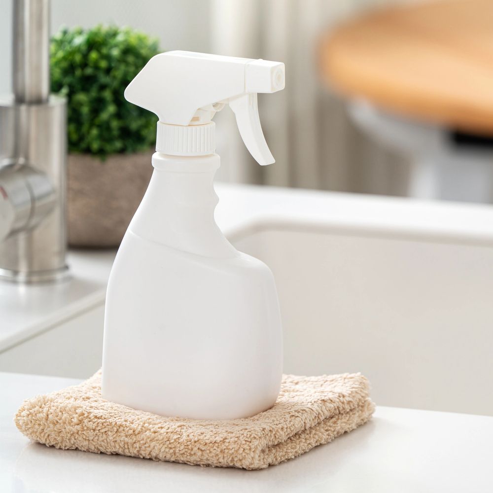 White spray bottle on a beige cloth near a kitchen sink.