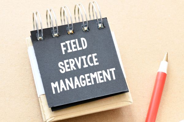 Notebook with 'Field Service Management' and a red pen.
