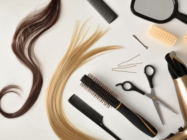 Hair styling tools and hair strands arranged on a white surface.