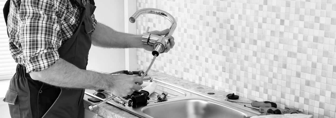 Plumber making kitchen faucet repair.