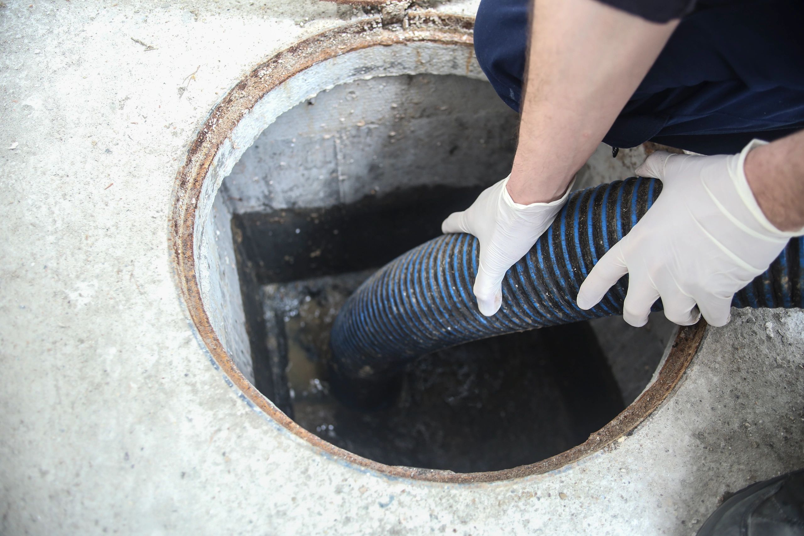 Technician servicing a septic tank opening